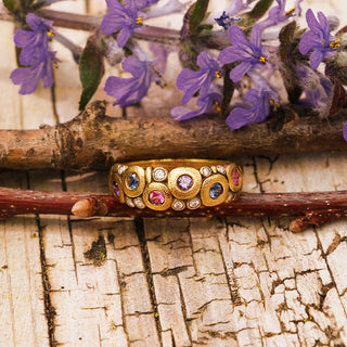 A painstakingly detailed 18K yellow gold dome ring, bedecked with colorful sapphires and shimmering diamonds.